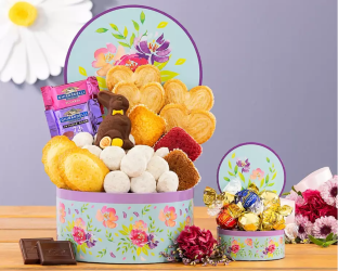 Decorative gift basket with teddy bears, candies, and flowers on a wooden table.