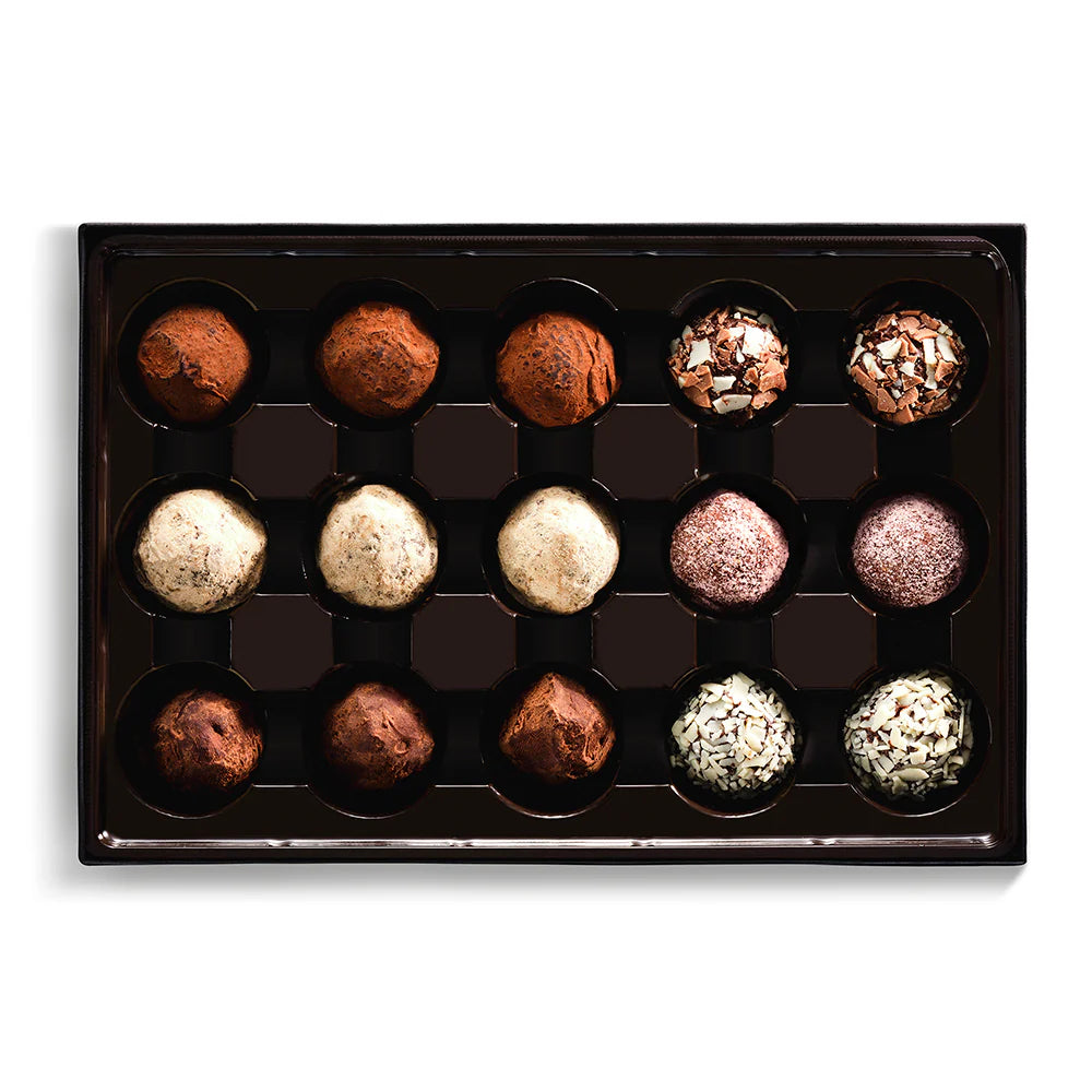 Assorted chocolate truffles in a black box on a white background