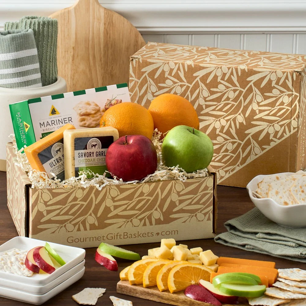 Gourmet gift basket with fruits, cheese, and crackers on a wooden table.