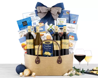 Gift basket with wine, cheese, and snacks on a table with glasses of red wine.