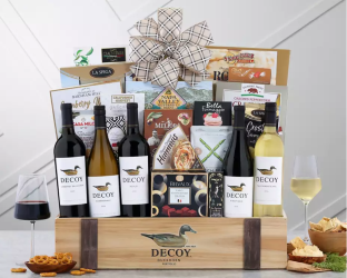 Gift basket with wine bottles, snacks, and a decorative bow on a wooden stand.