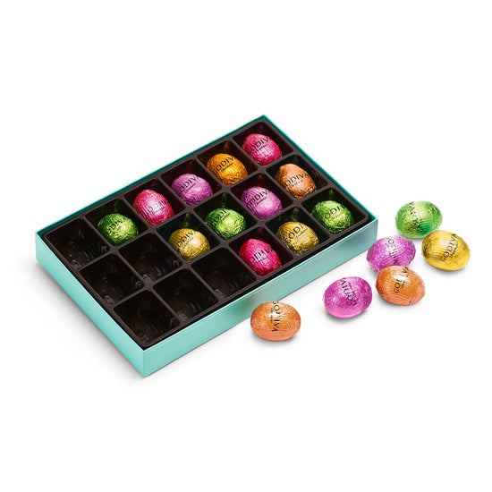 Assorted colorful chocolates in a green box on a white background