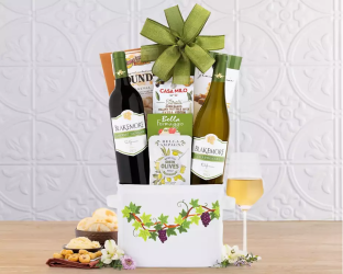 Gift basket with wine bottles, snacks, and a glass of white wine 