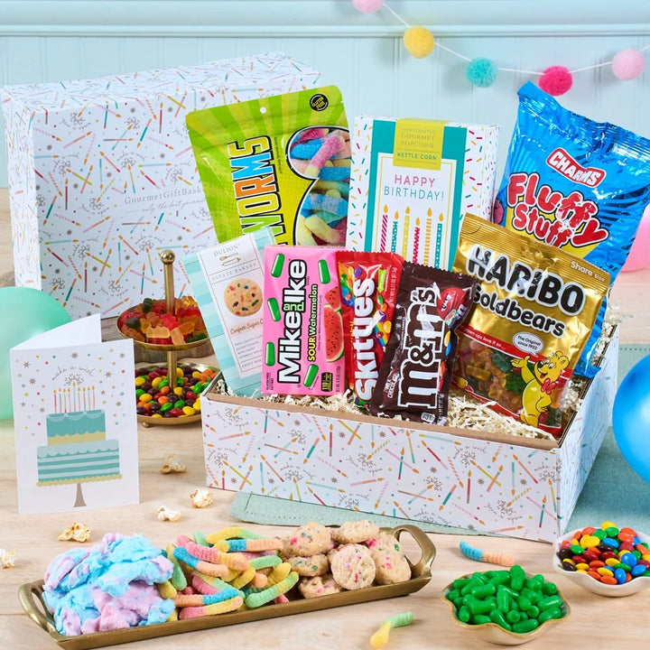 Assorted candy and snack box with birthday cards on a table.