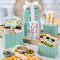 Gift basket with snacks and a 'Mom' card on a table.