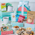 Assorted snacks and treats in colorful gift boxes with mugs and bowls on a white surface.