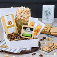 Gourmet gift basket with snacks and cookies on a table with a 'Best Mom in the World' card.