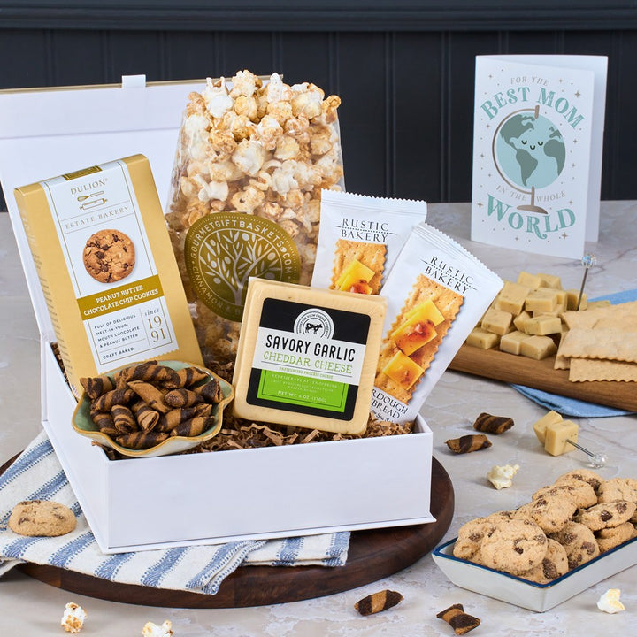 Gourmet gift basket with snacks and cookies on a table with a 'Best Mom in the World' card.