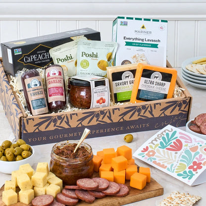Gourmet gift box with various food items including cheese, olives, and meats on a table.