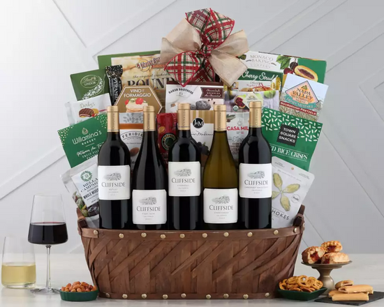 Wine gift basket with bottles, snacks, and a bow on a white background